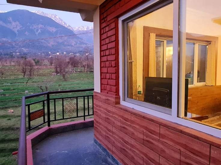 A Samdupling balcony looking across green fields to the Dhauladhar