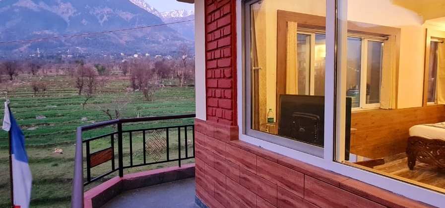A Samdupling balcony looking across green fields to the Dhauladhar