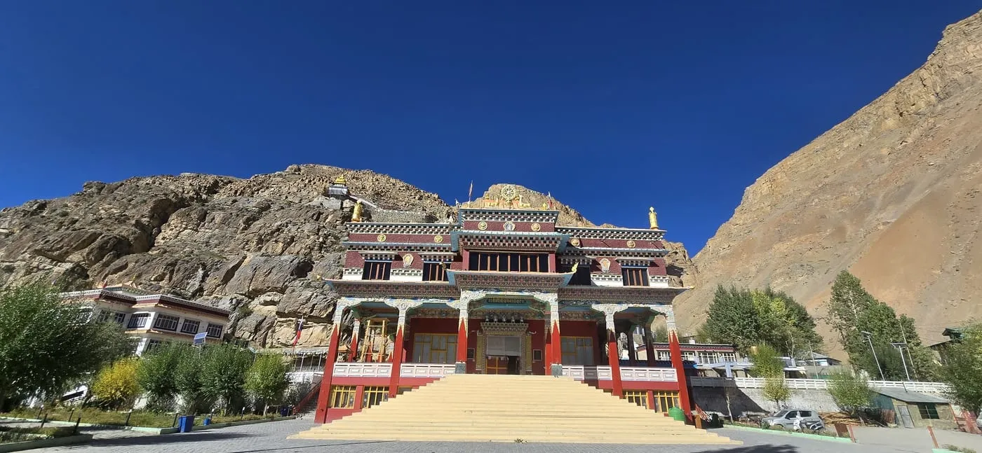 The Sakya monastery in Kaza, red and white with gold roof ornaments, under a deep blue sky