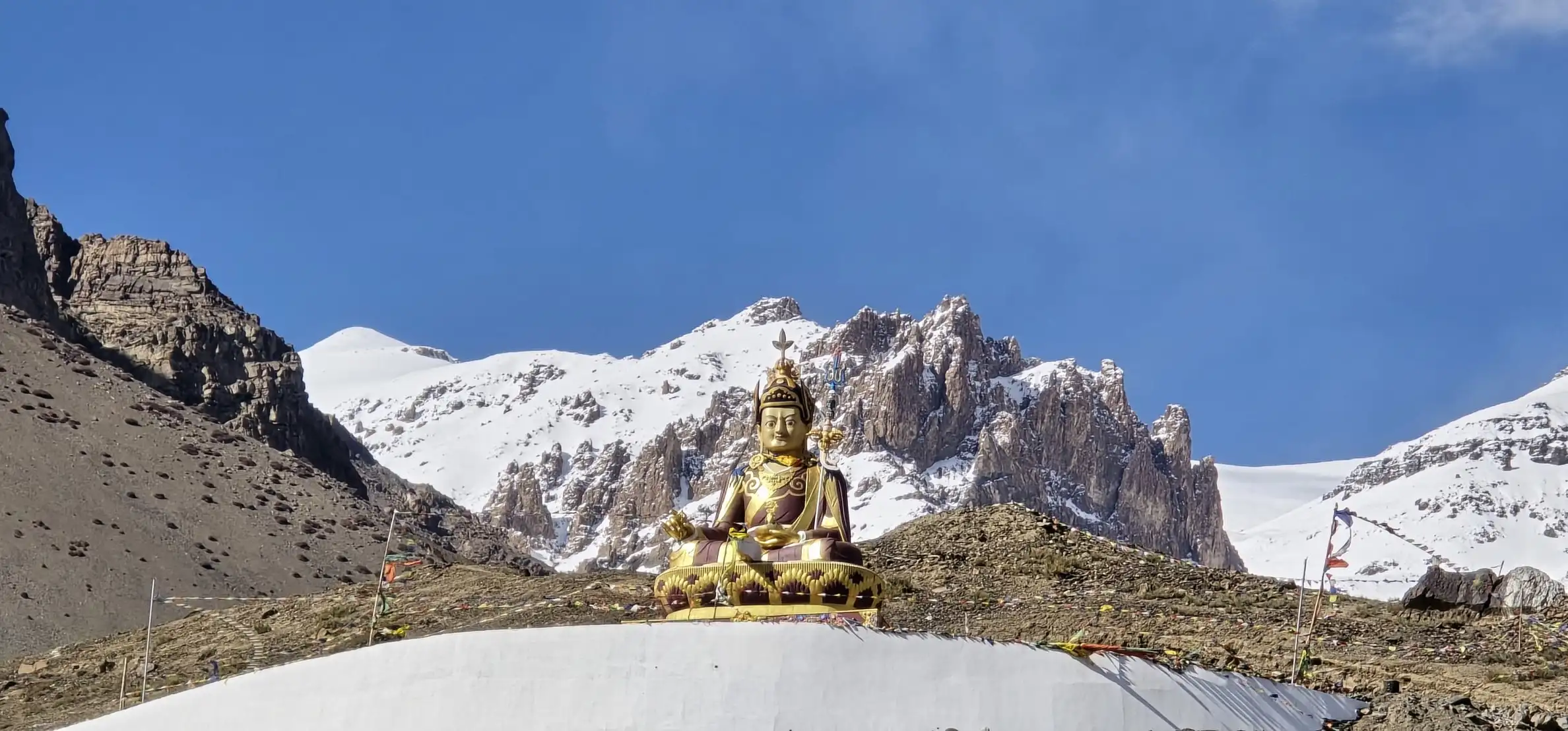 The golden Buddha statue at Langza, about 4,400 m up, below snowy peaks and a deep blue sky