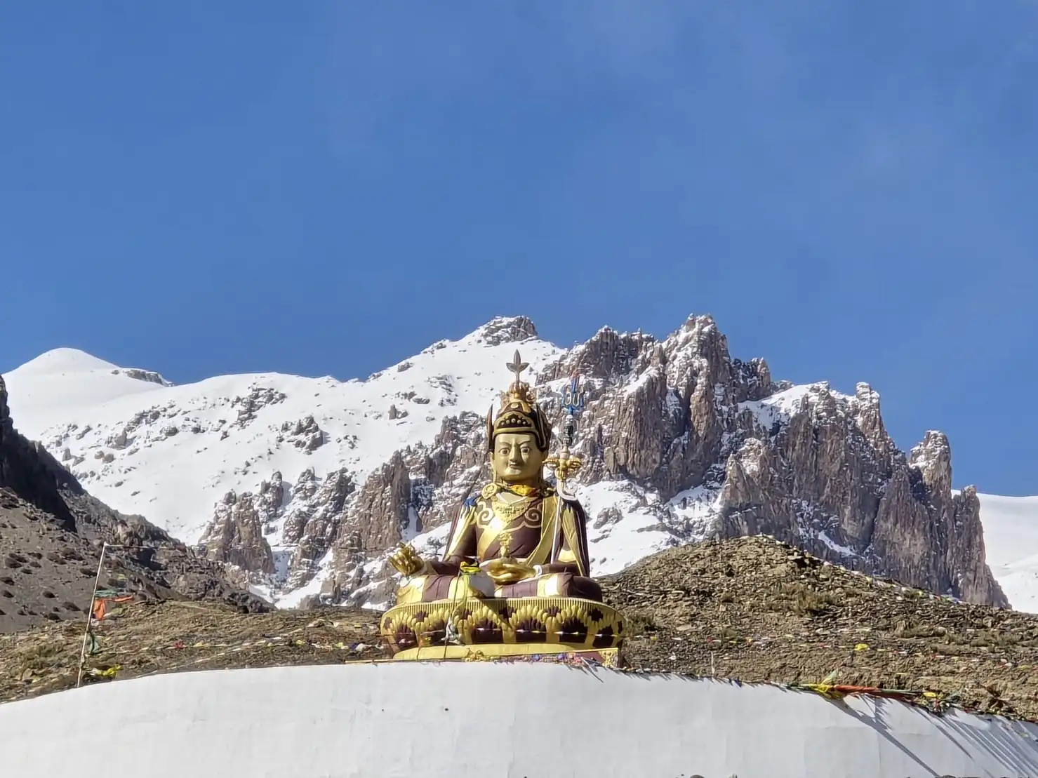 The golden Buddha statue at Langza, about 4,400 m up, below snowy peaks and a deep blue sky