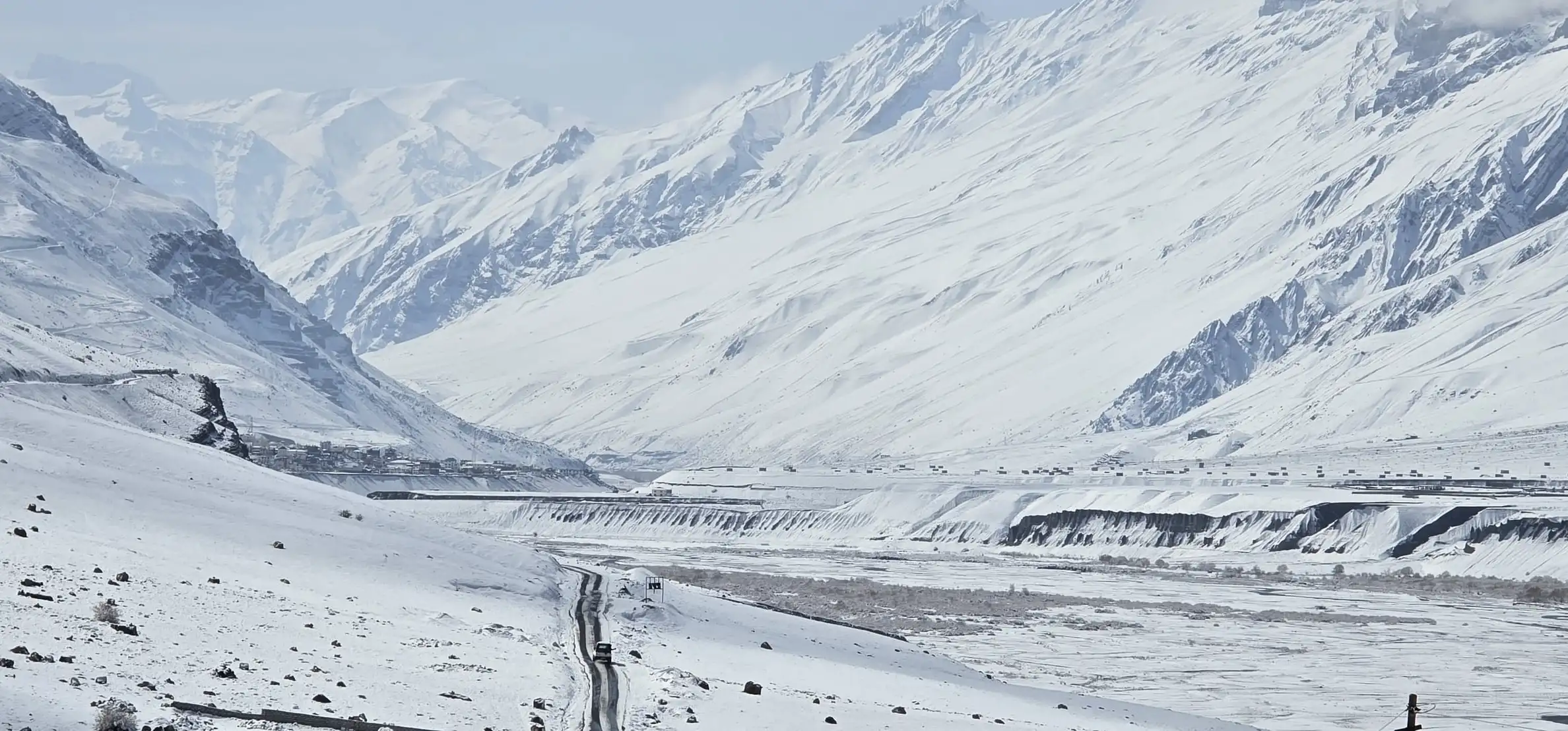 A narrow road through the snow-covered Spiti valley, with white mountains on every side