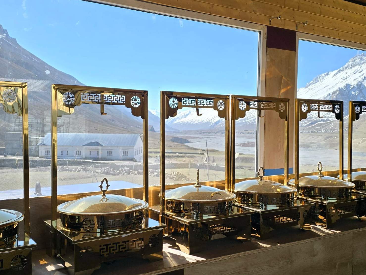 Brass buffet dishes by Spiti Villa’s restaurant windows, with snow peaks outside